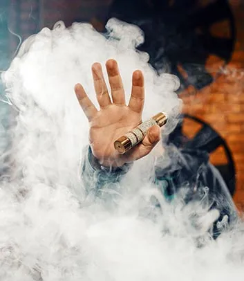 Palm of a hand emerging from thick smoke, holding a vaping device